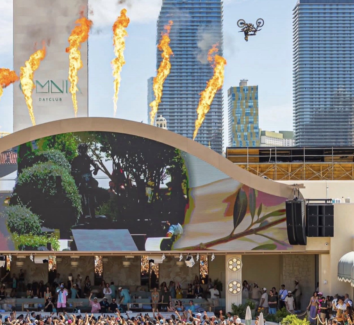 Colby Raha inverted mid-air over OMNIA Dayclub at Caesars Palace during the world-record motorcycle jump, flame jets firing below.